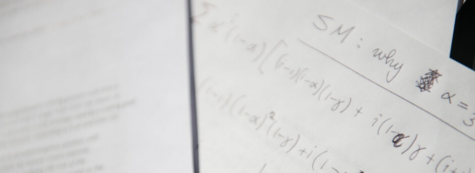 Blurred sheets of paper with handwritten equations; the words "SM: why" are legible at the top right